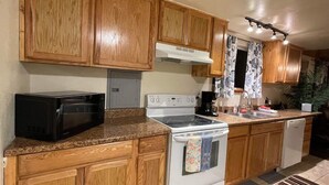 A kitchen with wooden cabinets, a microwave, an oven, and a dishwasher. - Sled Dog Cabin: Family, Pet Friendly Quiet Home in Wasilla (Wasilla)