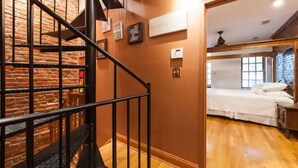A staircase with a brick wall, a bed with white bedding, and a wooden floor. - A Good Place To Stay! (Washington)