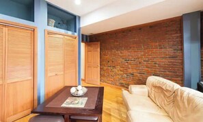A living room with a brick wall, wooden furniture, and a sofa.