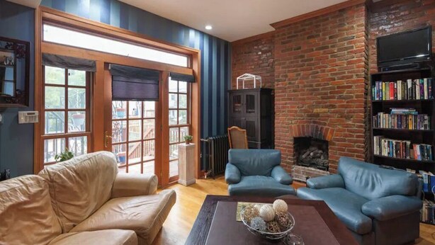 A cozy living room with a brick fireplace, leather sofas, a bookshelf, and a large window. - A Good Place To Stay! (Washington)