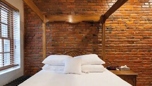 A bed with white linens and pillows, a wooden headboard, and a brick wall. - A Good Place To Stay! (Washington)