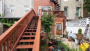 A wooden staircase leading to a small outdoor area with potted plants and a door. - A Good Place To Stay! (Washington)