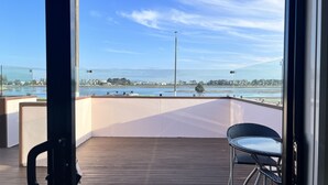 A balcony with a view of a waterfront, a chair, and a table. - Marineland Motel (Napier)