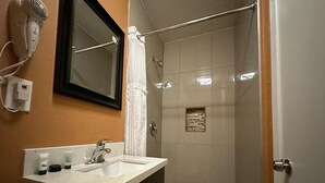 Een badkamer met wastafel, spiegel, haardroger en douche.