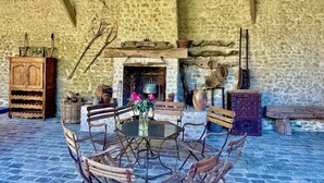A rustic stone interior with a round table, wooden chairs, a fireplace, and a wooden cabinet. - Elegant Mill Compound, 1 hr from Paris. Sleep 20, Events for 50 - an extra fee. (Méréville)