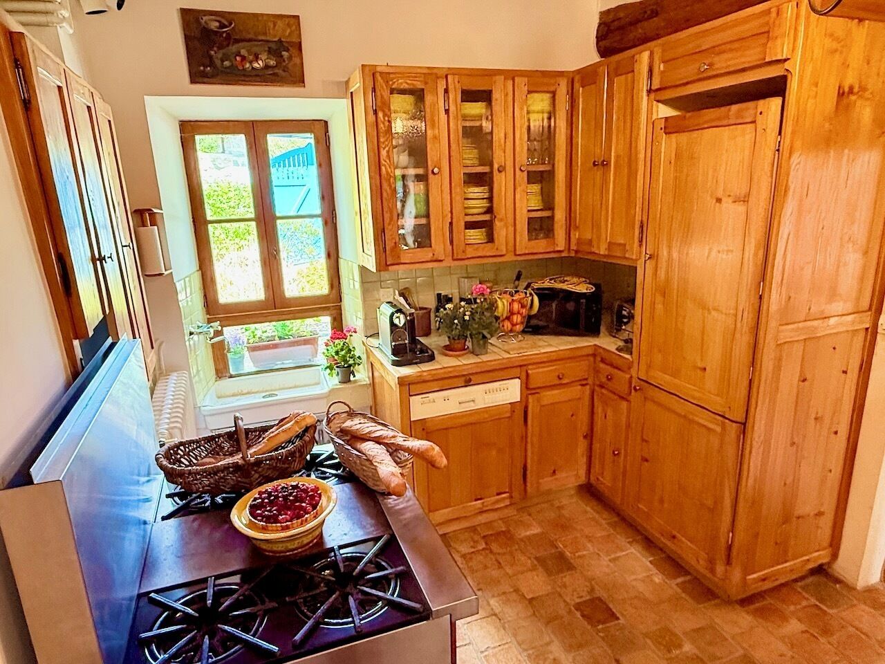 Una cocina con armarios de madera, una estufa y un ventanal con vistas al verdor.