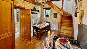 A rustic kitchen with a stone wall, wooden beams, a dining table set, and a fireplace. - Elegant Mill Compound, 1 hr from Paris. Sleep 20, Events for 50 - an extra fee. (Méréville)