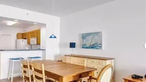 A modern kitchen with white cabinets, a wooden dining table, and a blue pendant light. - Luxury beachfront condo with magnificent views (North Redington Beach)