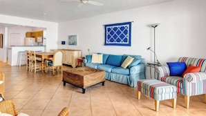 A spacious living area with a blue sofa, a wooden coffee table, and a striped ottoman. - Luxury beachfront condo with magnificent views (North Redington Beach)