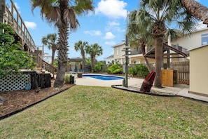 Zona residencial con piscina, palmeras y una terraza de madera.