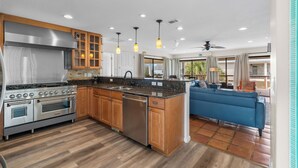 A modern kitchen with stainless steel appliances, wooden cabinets, and pendant lighting.