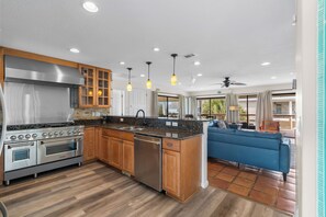 A modern kitchen with stainless steel appliances, wooden cabinets, and pendant lighting.
