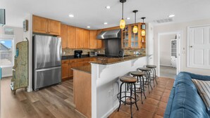 A modern kitchen with wooden cabinets, stainless steel appliances, and a central island with stools.