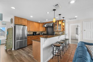 A modern kitchen with wooden cabinets, stainless steel appliances, and a central island with stools.