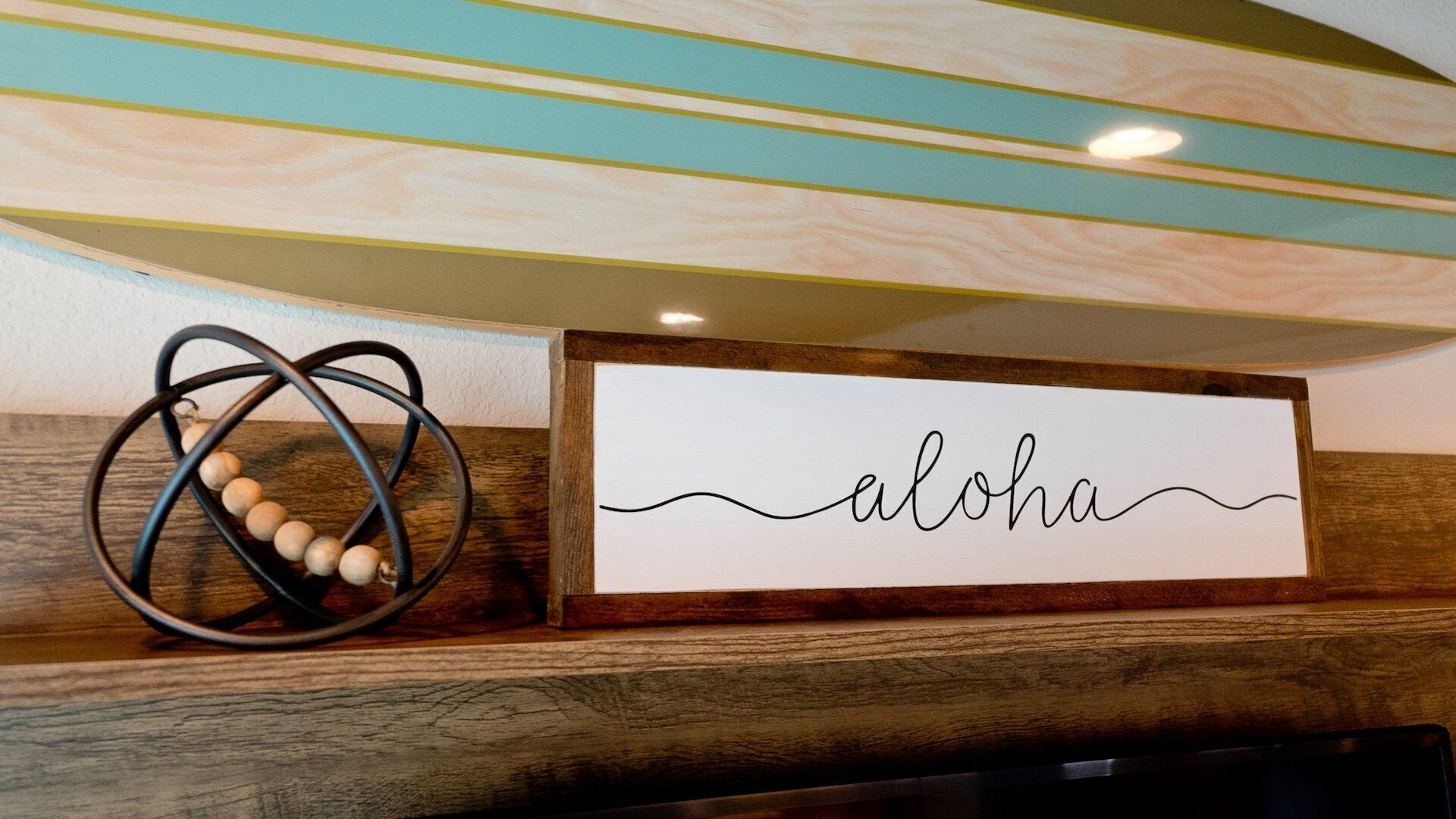Una estantería de madera con un letrero que dice "aloha" y un objeto decorativo de metal.