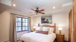 A bedroom with a bed, a ceiling fan, a window with curtains, a nightstand with a lamp, and a wooden wardrobe. - 2BR ski-in/out condo in Beaver Creek Village with mountain views (Beaver Creek)