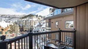 A balcony with a clear view of a snowy mountain town, featuring multi-story buildings and a road with parked cars. - 2BR ski-in/out condo in Beaver Creek Village with mountain views (Beaver Creek)
