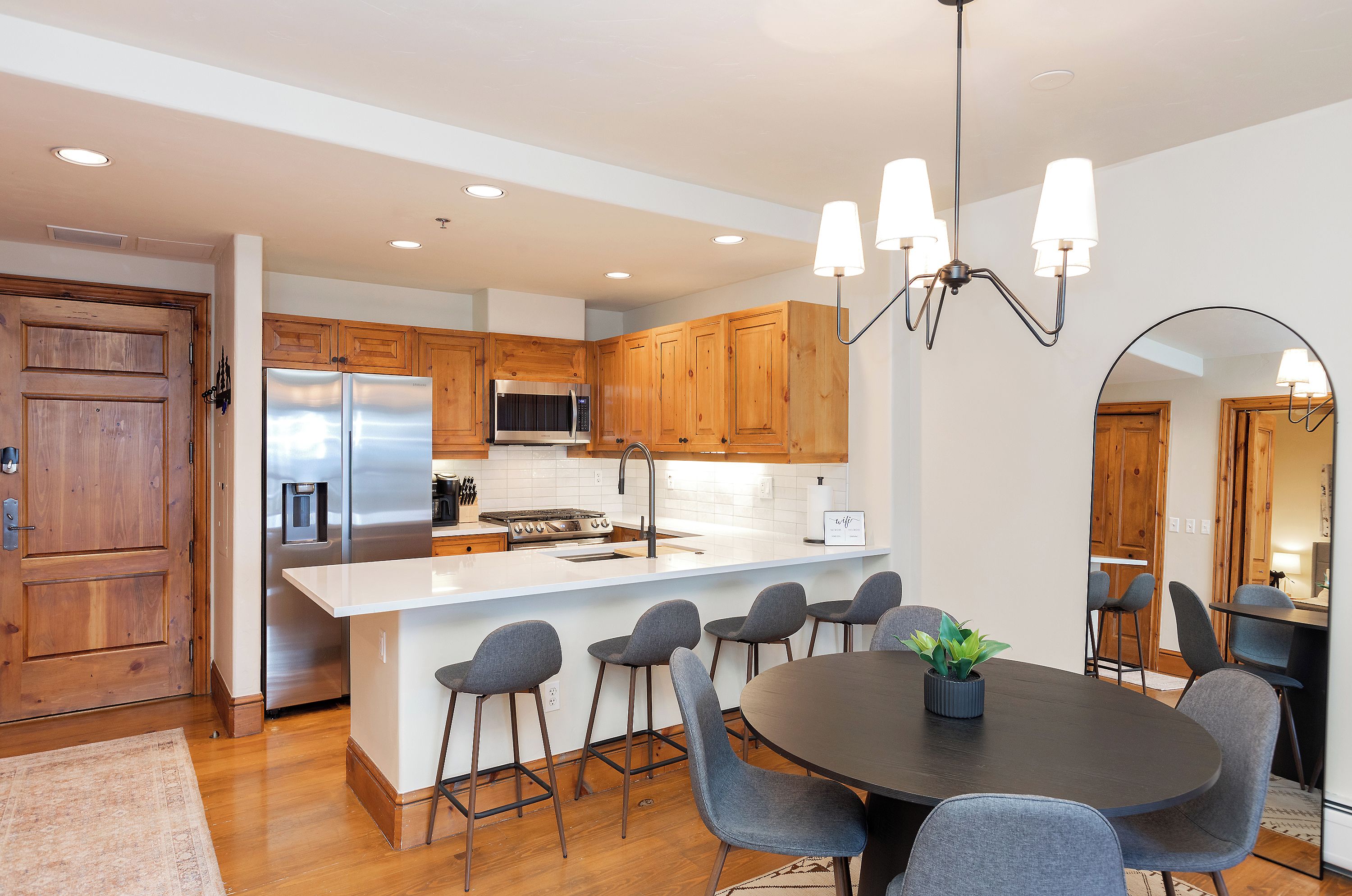 A modern kitchen with wooden cabinets, stainless steel appliances, and a central island with bar stools.