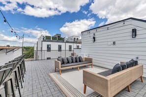 A rooftop patio with a wicker sofa and chairs, a metal railing, and a clear view of the surrounding buildings. - New Nashville Gem | Rooftop & Sleeps 11 (Nashville)