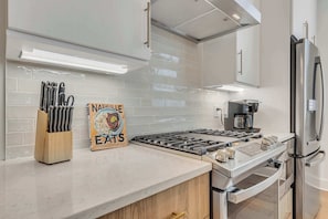 A modern kitchen with a gas stove, stainless steel appliances, and a coffee maker.