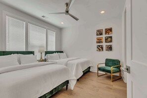 A hotel room with two beds, a ceiling fan, and a green chair.