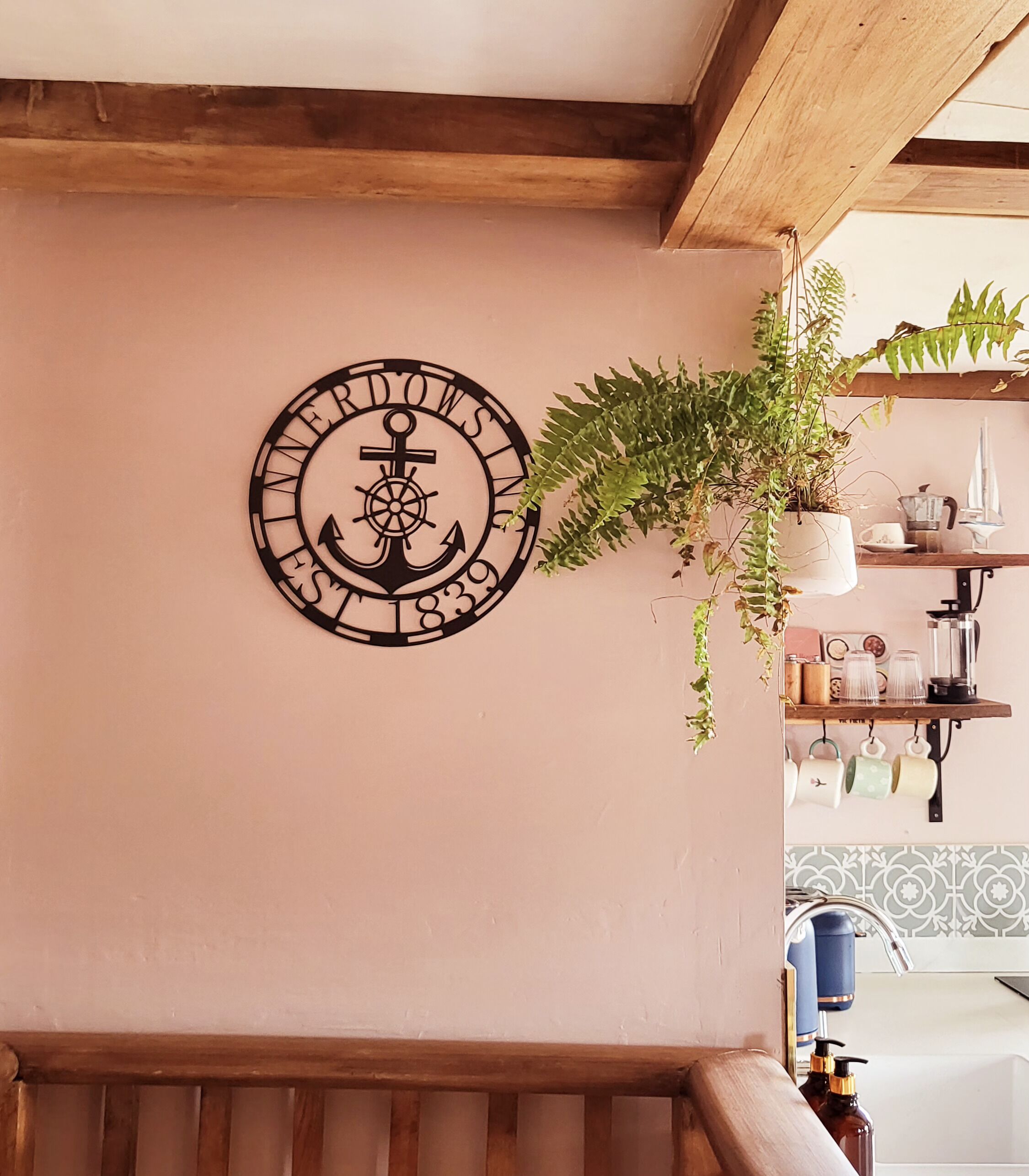 A wall with a nautical-themed anchor decoration and a hanging plant.