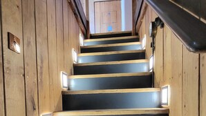 A wooden staircase with built-in lighting, leading to a door at the top. - Inner Dowsing Lightship (Rochester)