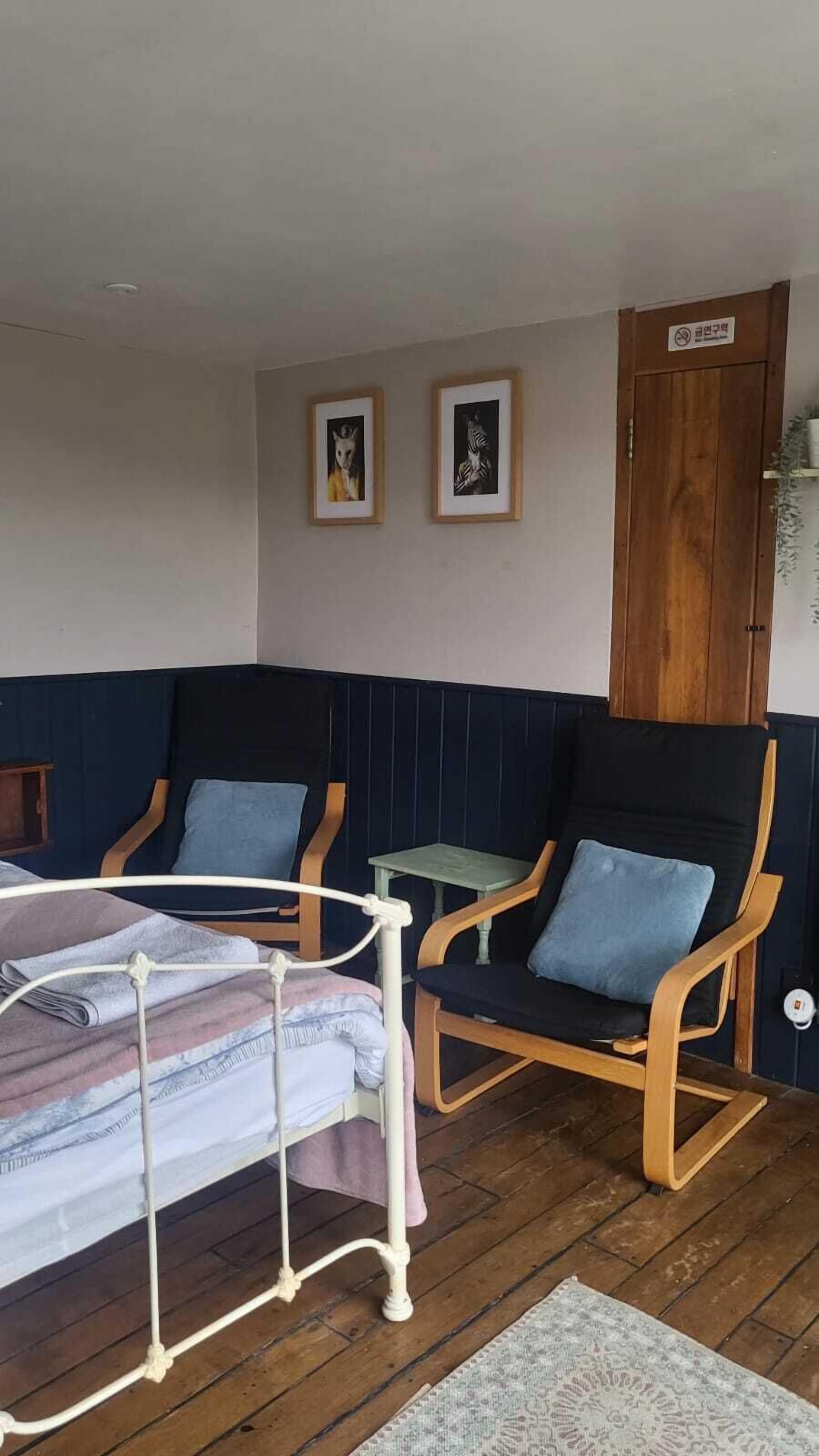 Una habitación con dos mecedoras, una cama con estructura de metal y una puerta de madera.