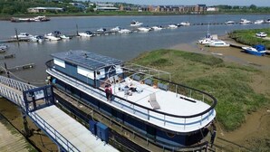 A riverboat with a covered deck and a dining area, docked at a marina with several boats. - Inner Dowsing Lightship (Rochester)