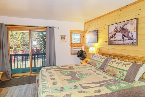 Un dormitorio con una cama grande, un balcón con vistas, un ventilador y un cuadro de animales.