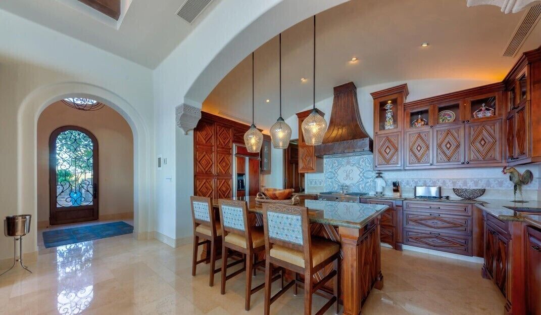 A spacious kitchen with wooden cabinets, a large island, and pendant lighting.