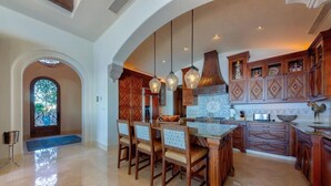 A spacious kitchen with wooden cabinets, a large island, and pendant lighting.