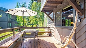 A wooden deck with a table and chairs, a bench, and a large umbrella. - Wildwood Cottage at Villager + SV Resort Amenities (Sun Valley)