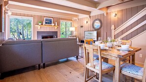 A cozy living room with a sofa, a dining table set for four, and a fireplace. - Wildwood Cottage at Villager + SV Resort Amenities (Sun Valley)