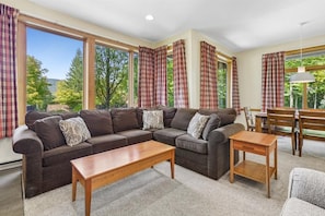 Living Room Surrounded by Windows - Large windows wrap around the living area, bringing in abundant natural light and views of the wooded mountain surroundings.