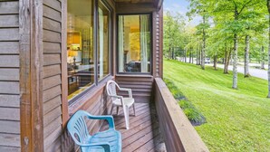 A wooden house with a porch, two chairs, and a view of a green lawn and trees. - Inviting Country Setting with access to sports center, pool, hot tub - Highridge D18 (Killington)