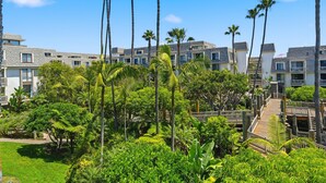 Un resort con edificios de varios pisos, abundante vegetación y un paseo central.
