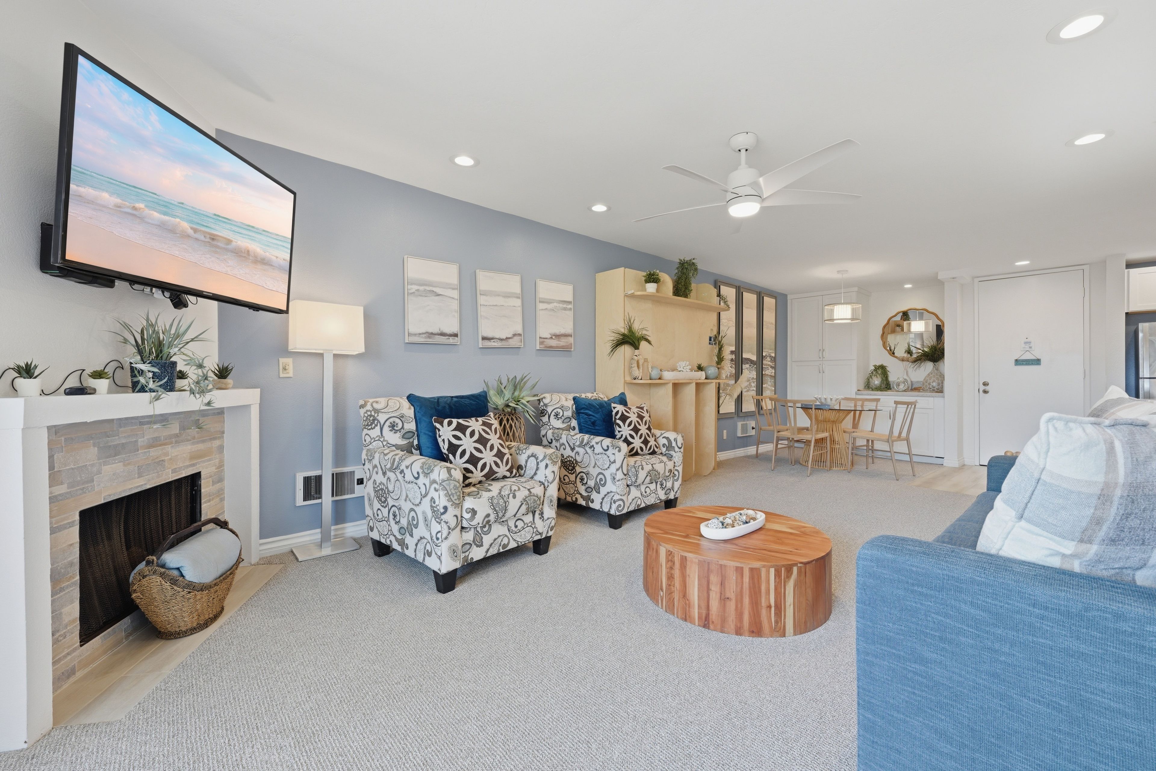 A living room with a fireplace, sofas, a coffee table, and a television mounted on the wall.