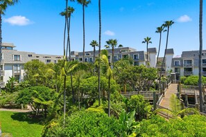 A resort with multiple-story buildings, lush greenery, and a clear blue sky. - G224 North Coast Village - 1 bdrm condo super close to the beach! (Oceanside)