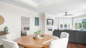 A spacious living area with a wooden dining table, white sofas, and a fireplace. - Point of View by SoCharm | Luxury Lakefront Condo | Deck | Sleep 6 (Mooresville)