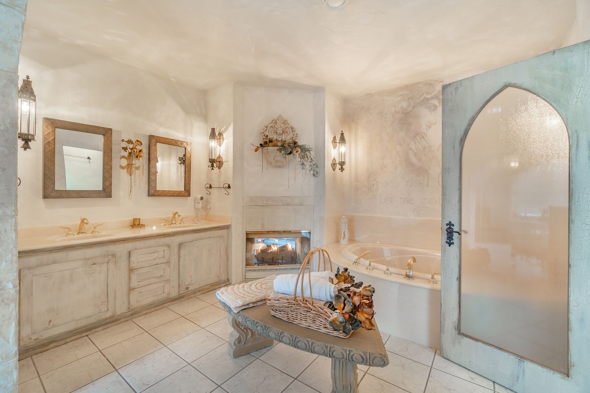 A spacious bathroom with a large vanity, a bathtub, and a fireplace.