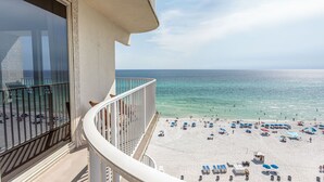 Ein Balkon mit Blick auf einen Strand mit Sonnenschirmen und Liegestühlen.