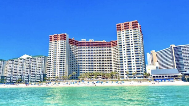 Ein Hotel am Strand mit mehreren Hochhäusern, einem Sandstrand und blauem Himmel.