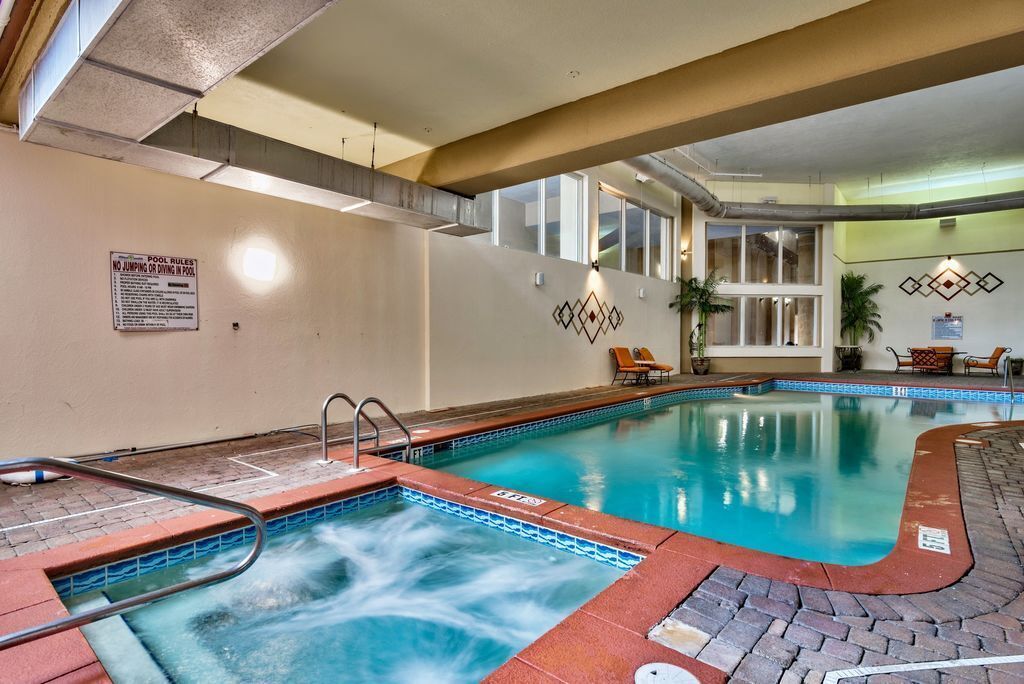 Une piscine intérieure dotée d’un jacuzzi, de chaises longues et d’un espace aménagé au bord de la piscine.