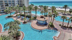 Ein Resort mit mehreren Schwimmbecken, Palmen und Blick auf den Strand.