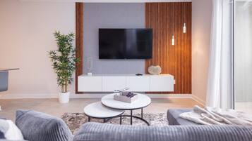 Ein modernes Wohnzimmer mit Flachbildfernseher an der Wand, einem runden Couchtisch und einer Couch.