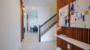 Een modern interieur met een trap, houten lambrisering en abstracte kunst aan de muren.
