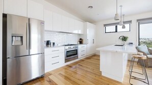 A modern kitchen with white cabinetry, stainless steel appliances, and a central island.