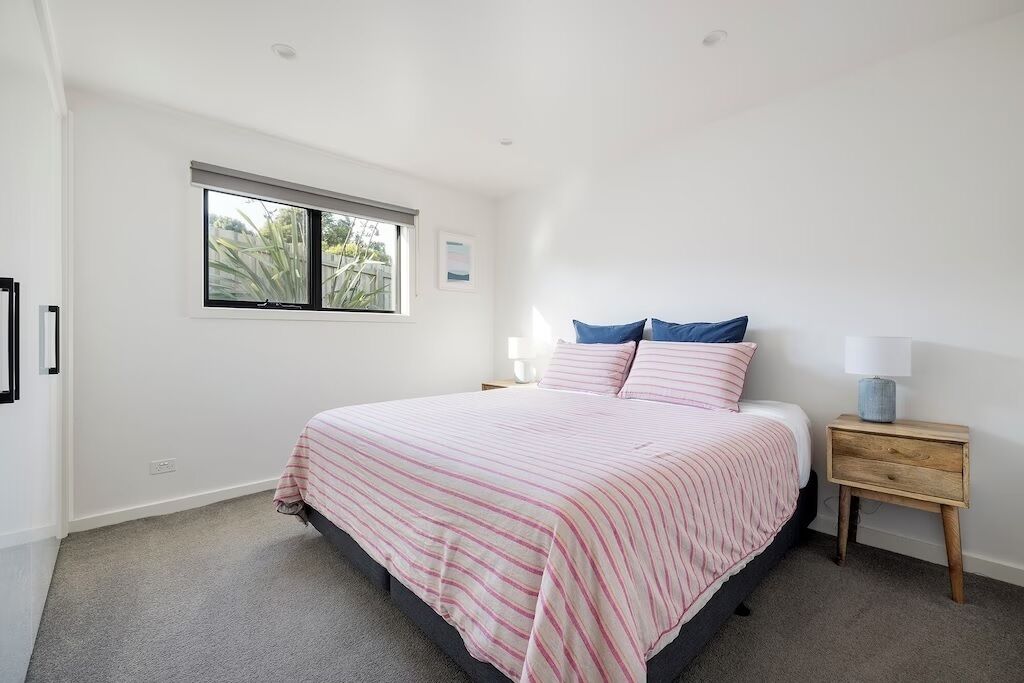 Une chambre à coucher avec un lit, une table de chevet, une lampe et une fenêtre.
