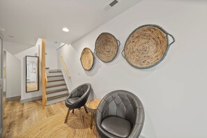 A modern interior with a staircase, a black leather chair, and three woven wall art pieces. - A Red Chalet - Linville mountain chalet with game room, fireplace & year-round views (Newland)